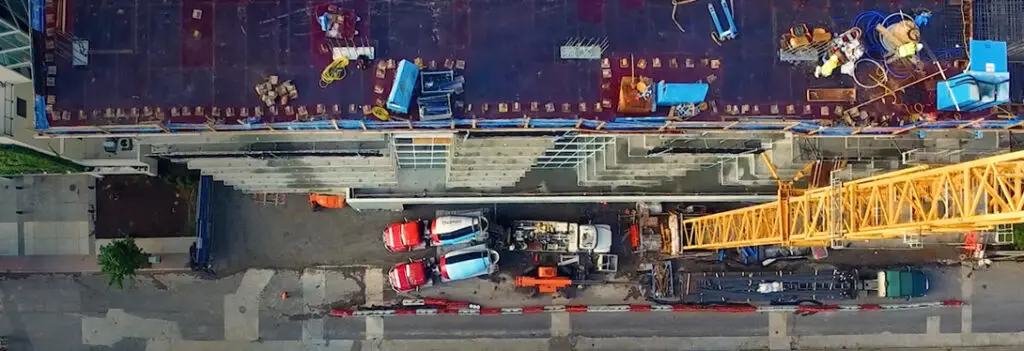 Top down view of construction site for building with two concrete mixer trucks in view.
