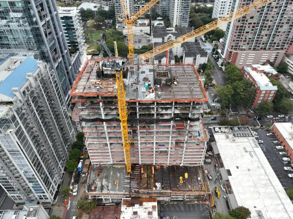 High-rise building under construction with cranes in the foreground.