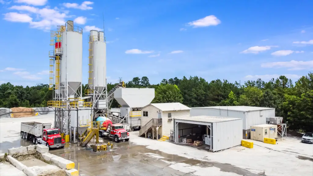 Dump truck and concrete mixer near gray silos
