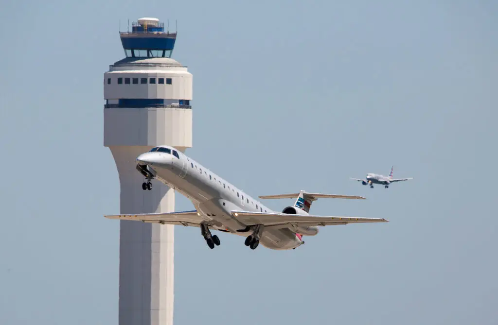 Airplane ascending with control tower in the background