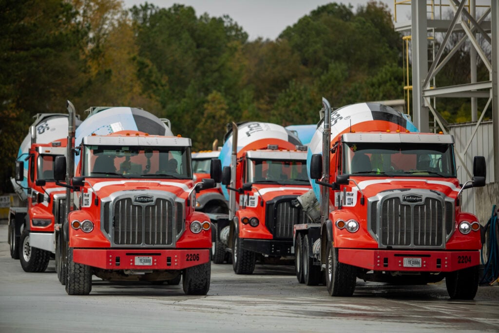 Two rows of red and blue concrete mixer trucks