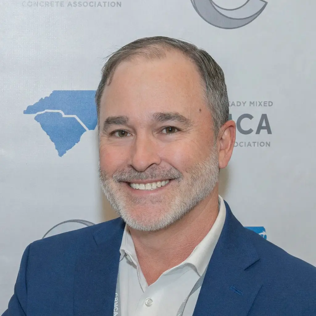 Man in white shirt and navy blue jacket smiling