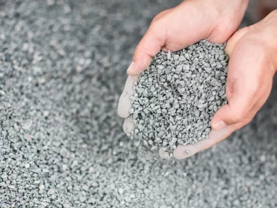 Hands holding pile of gravel.